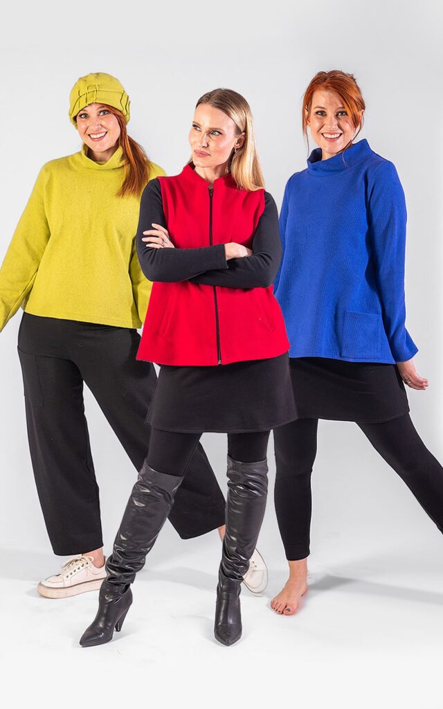 Three people in bright yellow, red, and blue tops with black bottoms and varied footwear standing in a row.