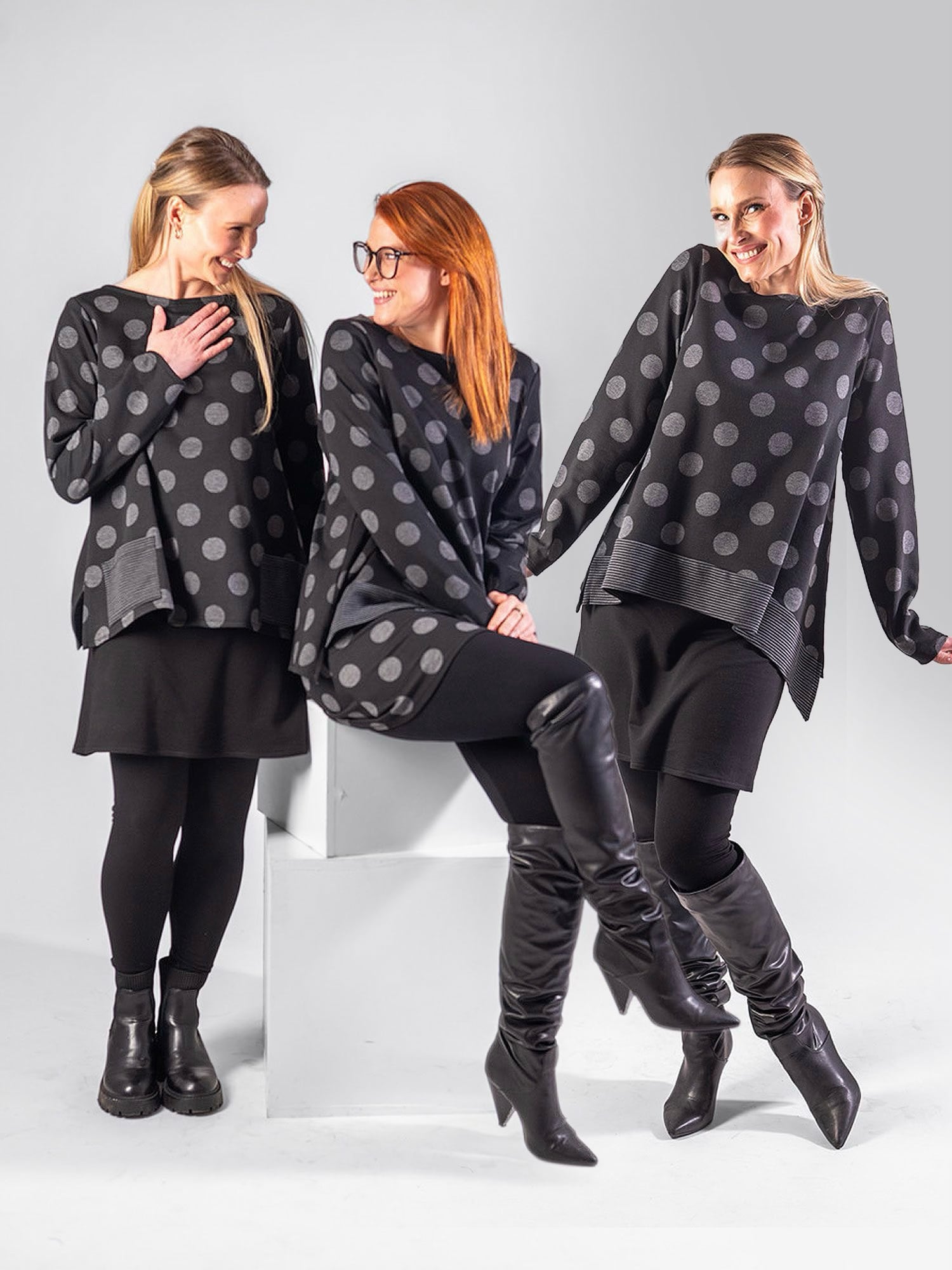 Three people wearing matching black tops with large gray polka dots, black bottoms, and black boots posed against a light background.